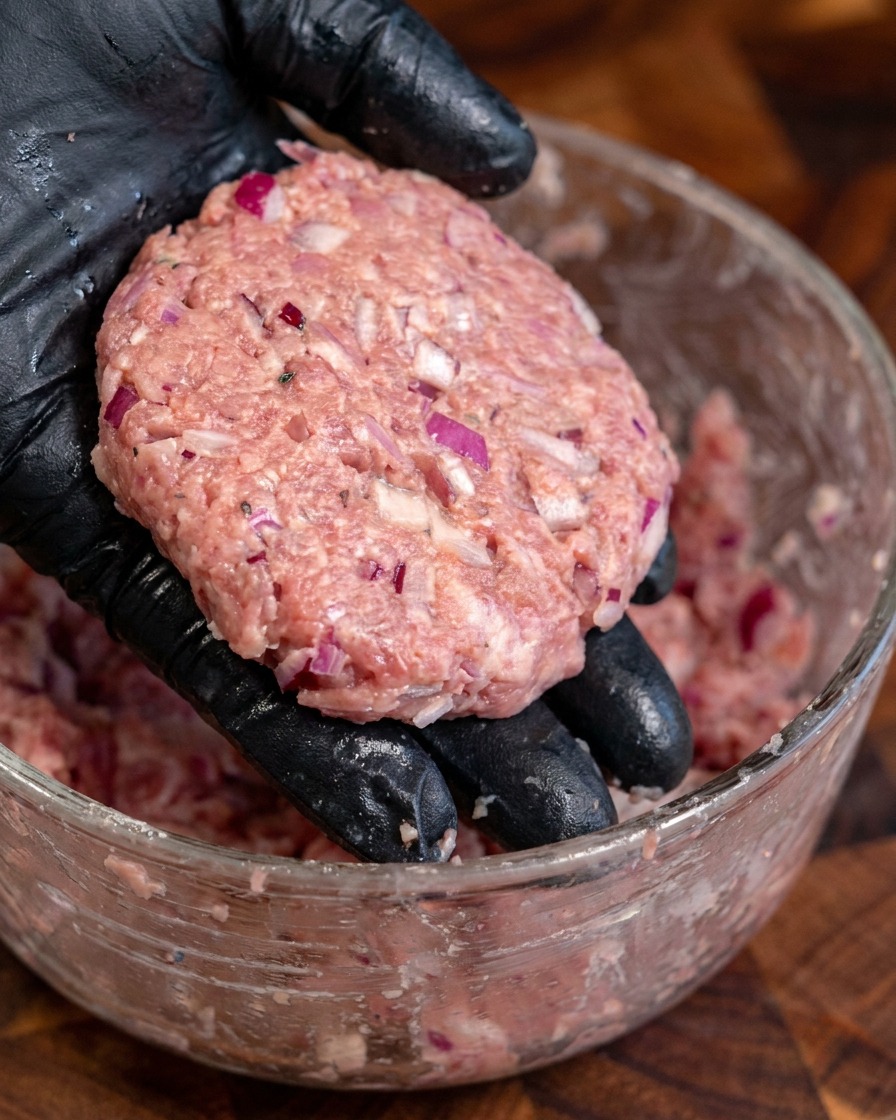 Diversi hamburger di manzo spessi e rotondi modellati a mano.
