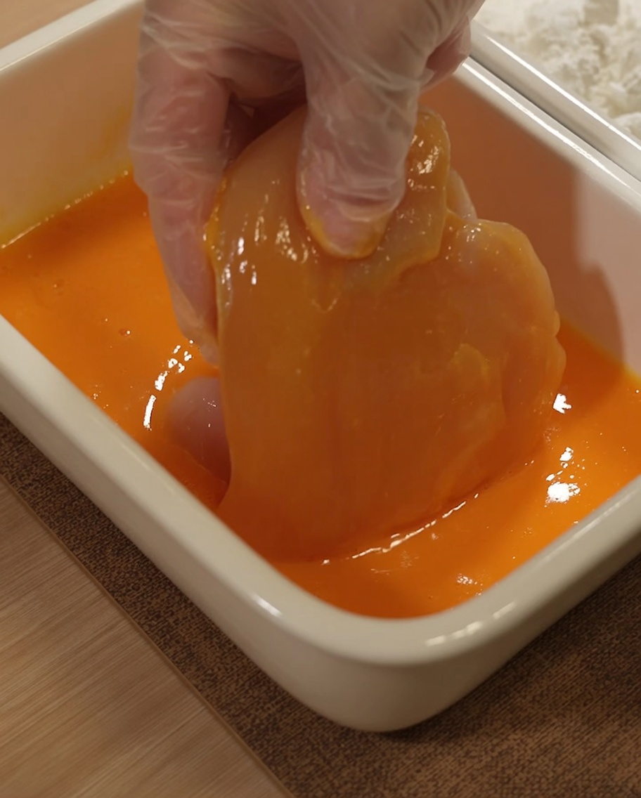 Petto di pollo immerso in una miscela di uova sbattute.