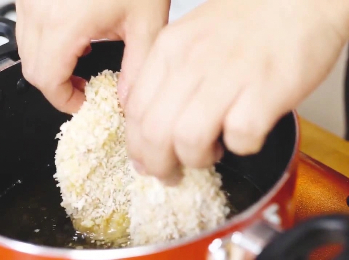 La cotoletta di pollo impanata frigge in una padella con olio bollente fino a doratura.