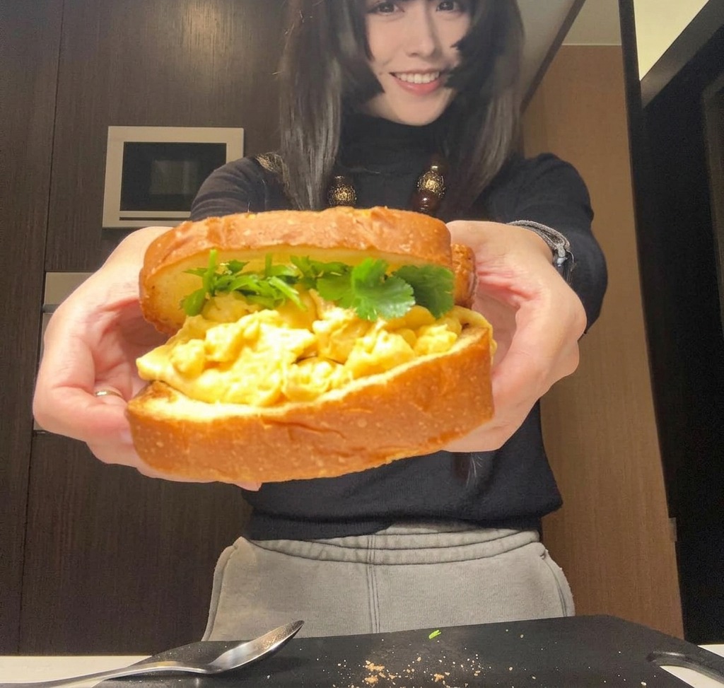 Un panino completamente assemblato tenuto con due mani, pronto per essere avvolto o affettato.