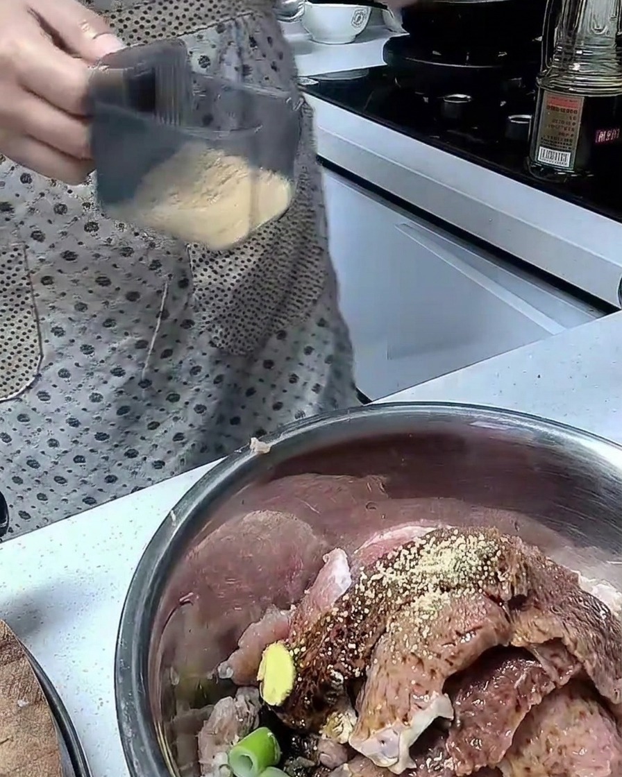 Ingredienti mescolati con fette di maiale crudo in una ciotola di acciaio inox.
