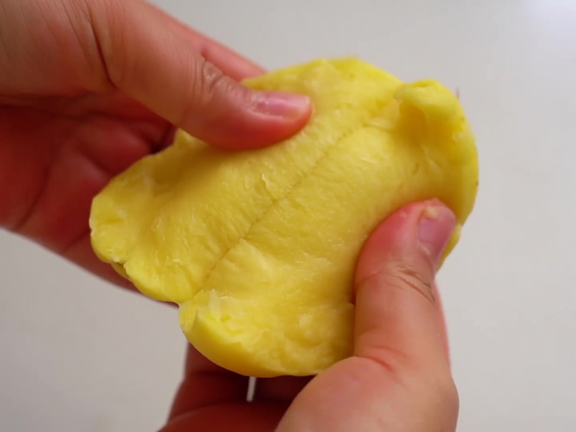 Mani che dividono una patata pelata in due metà irregolari.