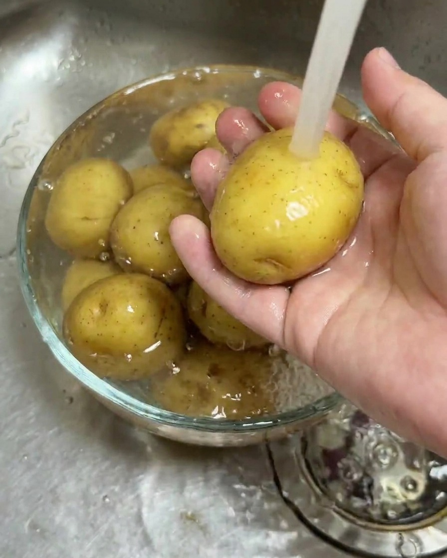 Patatine novelle in una ciotola di vetro sotto lacqua corrente.