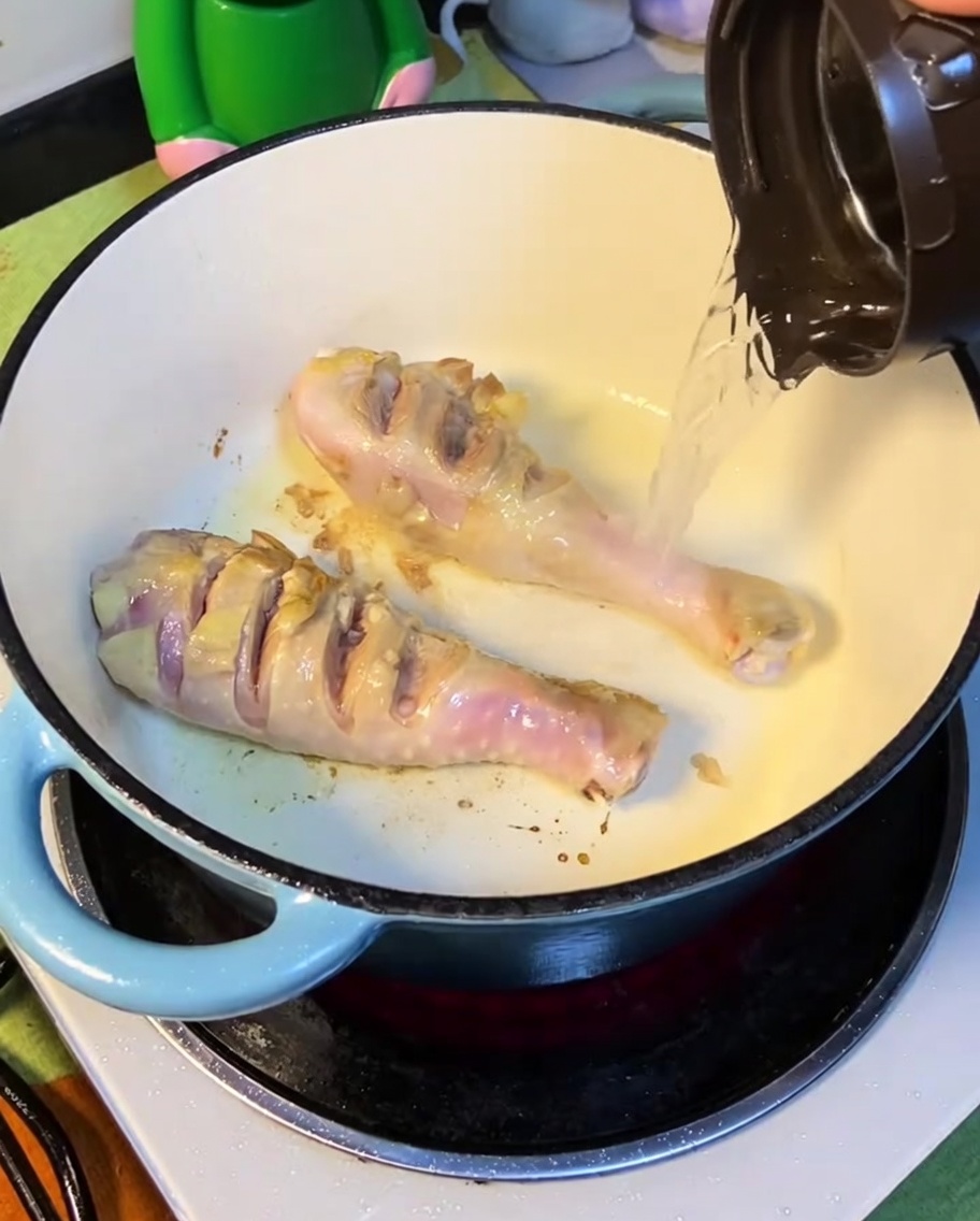 Acqua bollente versata nella pentola con il pollo rosolato.