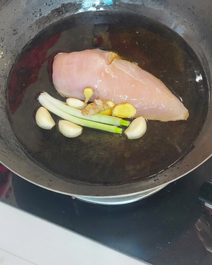 Il pollo cotto estratto dal wok con una schiumarola e bacchette.