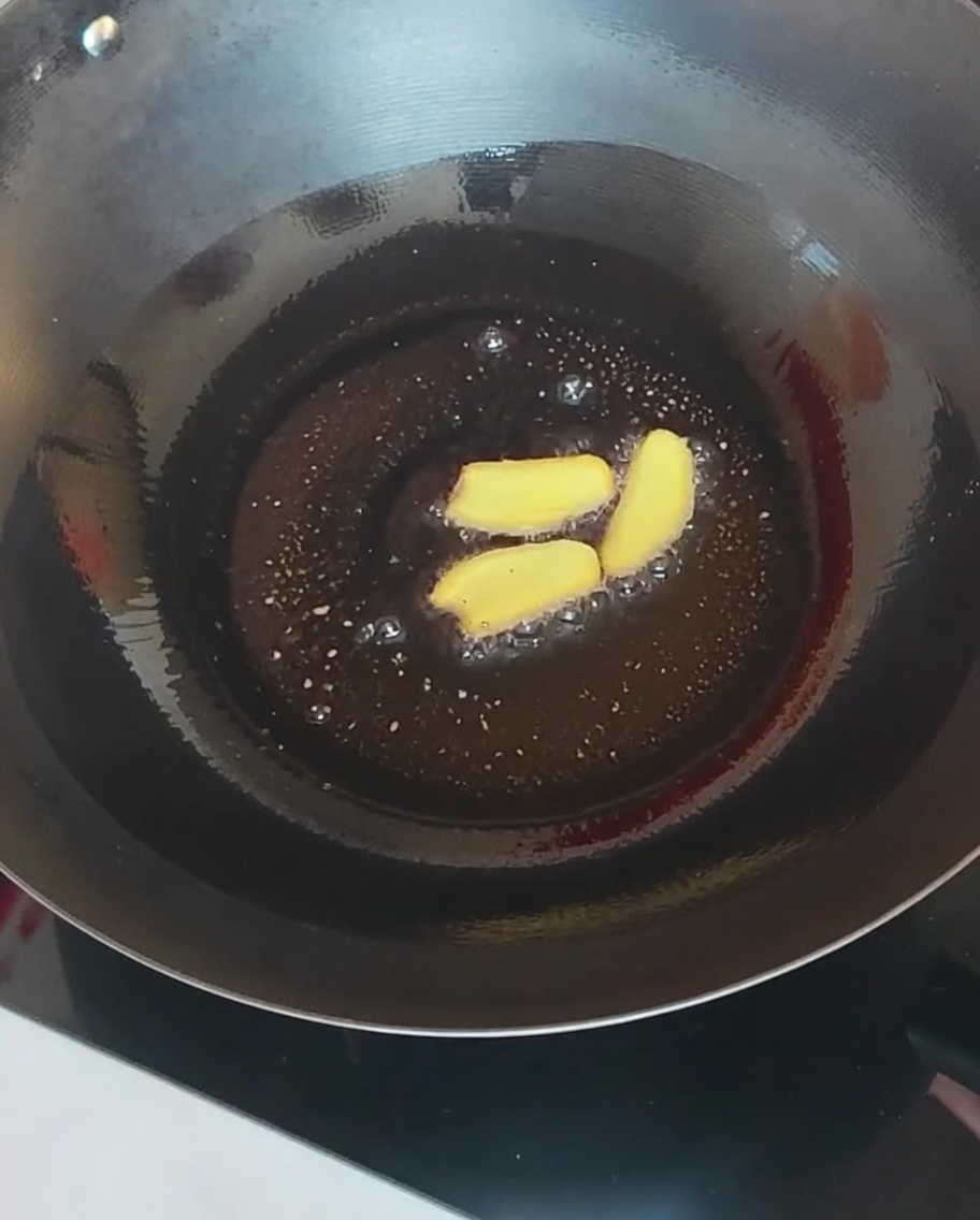 Fette di zenzero e funghi vari saltati in un wok caldo.