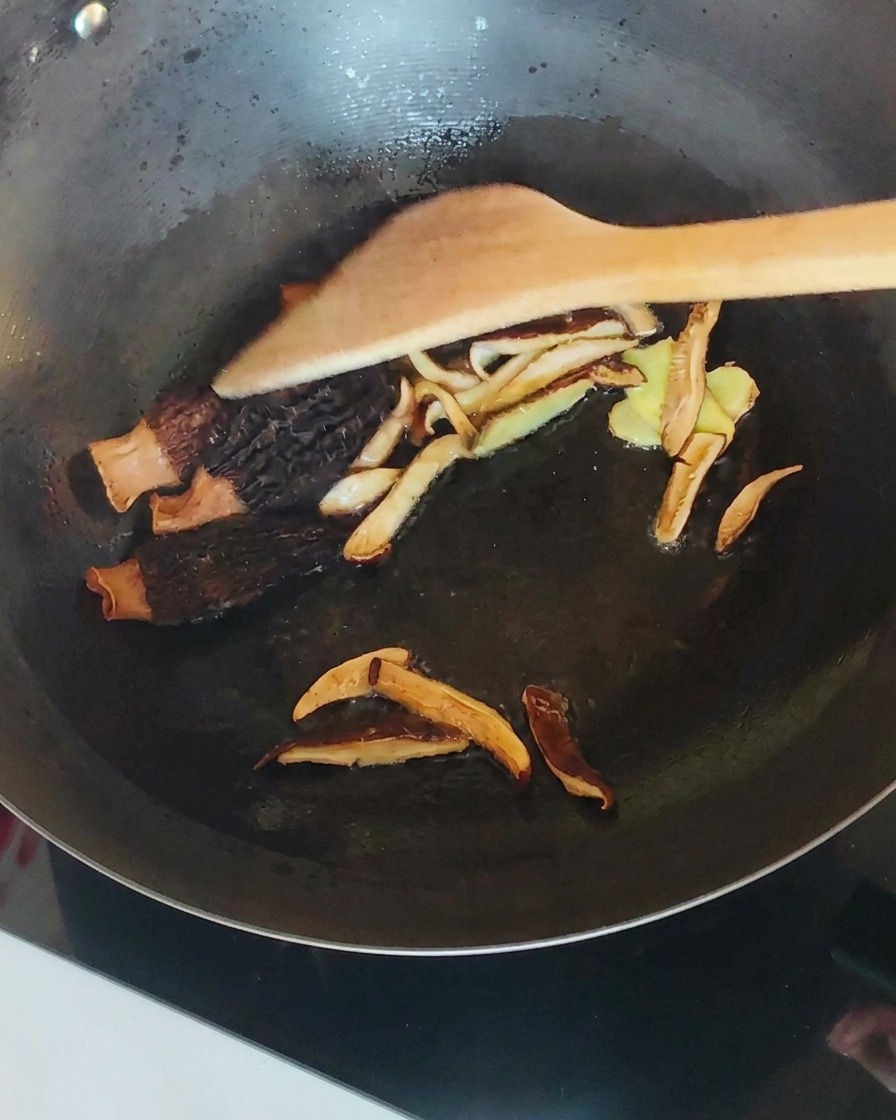 Pollo sfilacciato mescolato con funghi e zenzero nel wok.