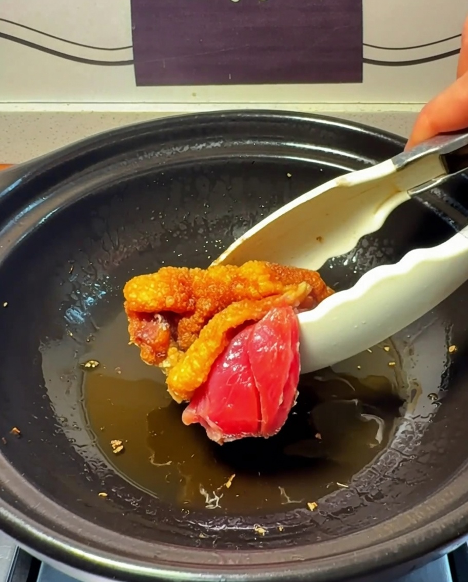 Pezzi di pollo che rosolano nel tegame di terracotta.