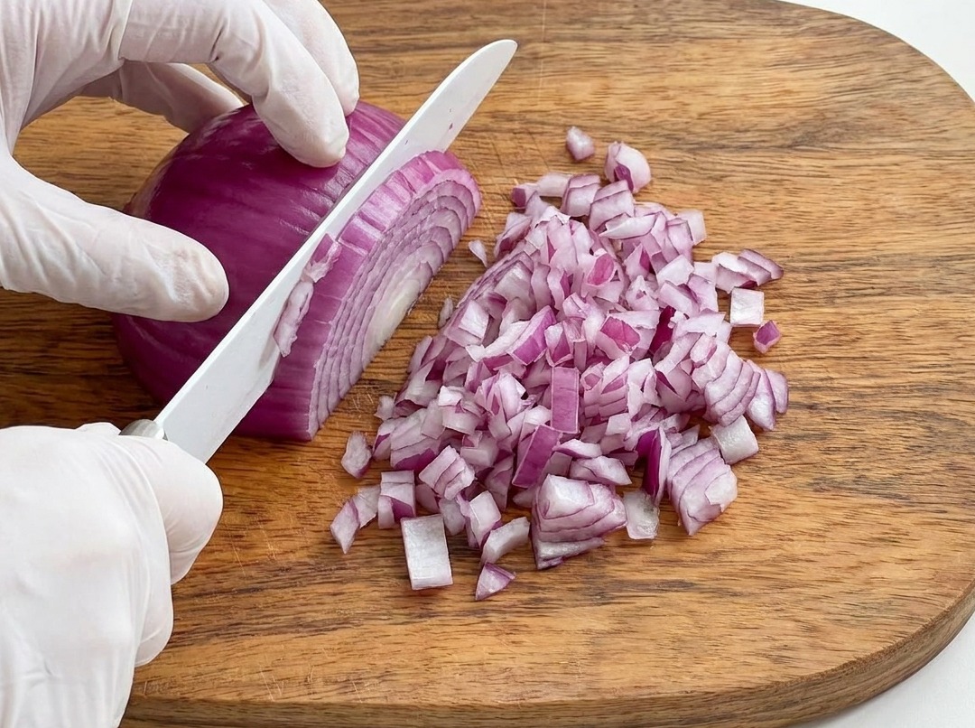 Cipolla rossa tritata finemente su un tagliere di legno.
