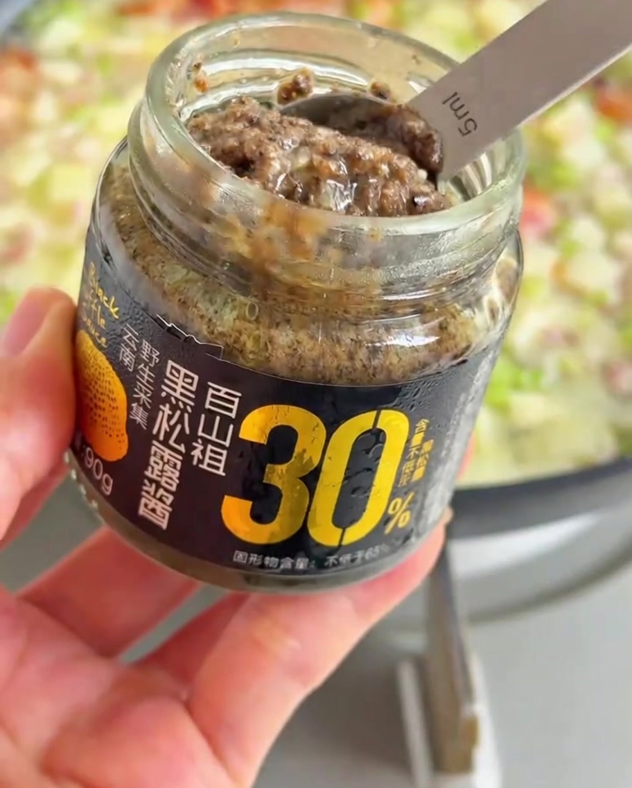 Un cucchiaio di densa salsa al tartufo nero aggiunto alle verdure in leggera ebollizione.