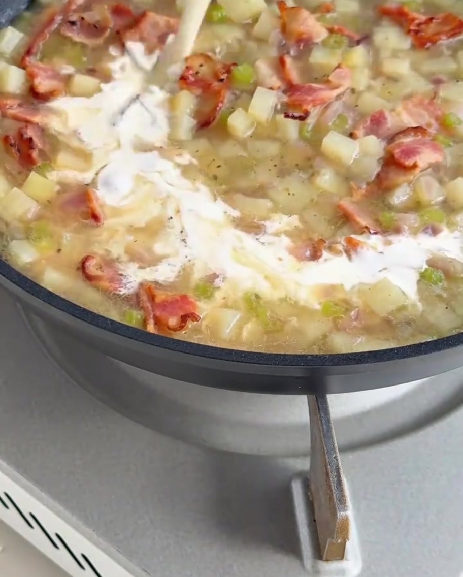 Crema bianca densa versata nella zuppa base in ebollizione.