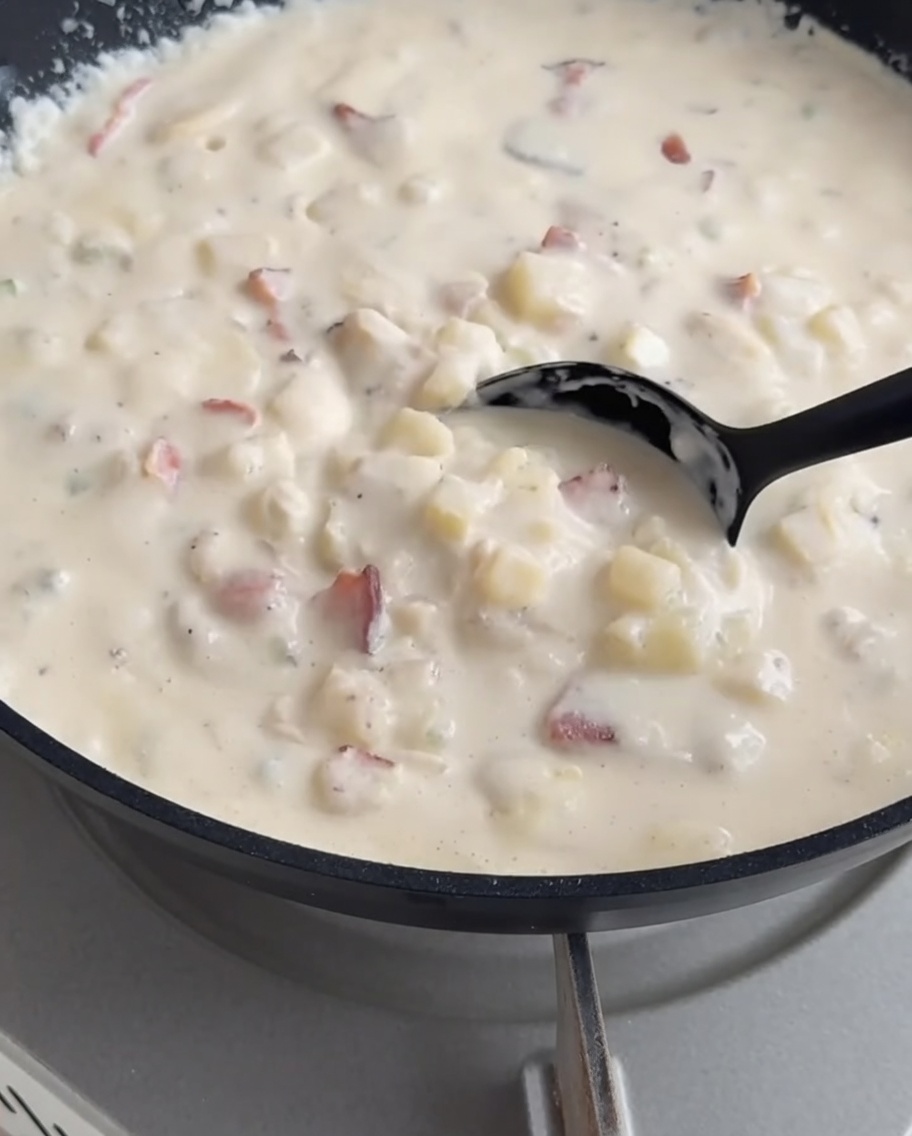 La clam chowder cremosa viene versata con un mestolo allinterno della pagnotta scavata.