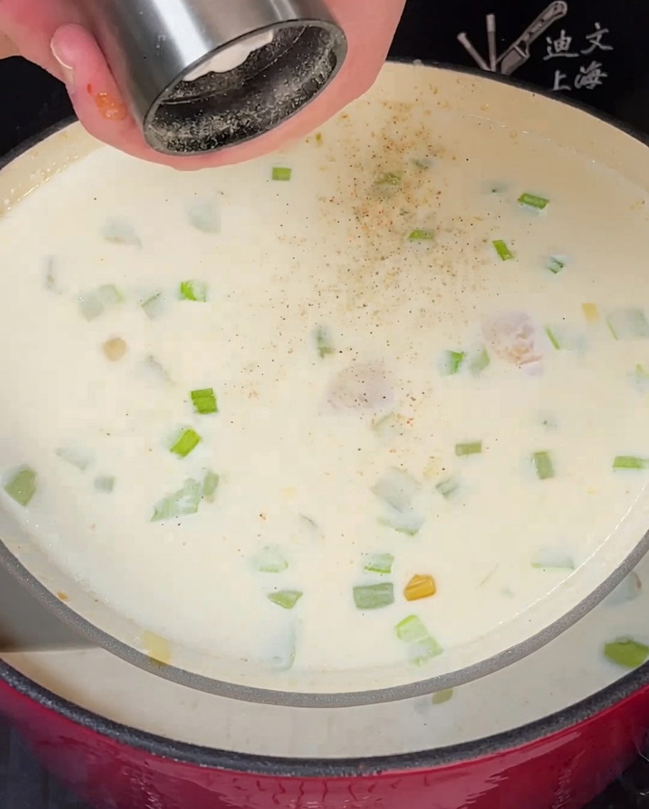 Foglia di alloro e timo fresco aggiunti in una pentola di cremosa zuppa di vongole.