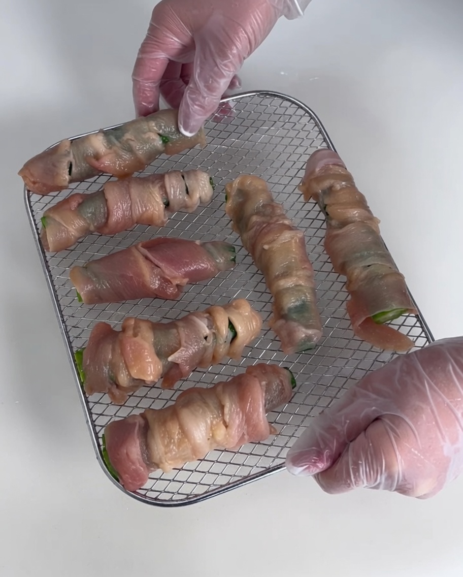Diversi involtini di pollo ed okra disposti su una griglia metallica.