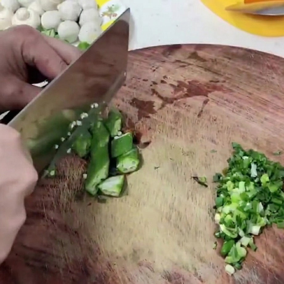 Segmenti di okra verde fresca tagliati su un tagliere di legno.
