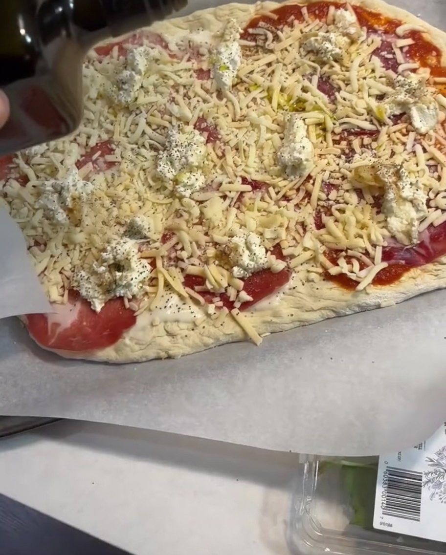 Un leggero filo dolio doliva applicato sopra gli ingredienti della pizza.