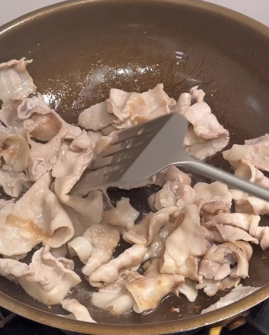 Cipolla, cipollotti e fette di peperoncino aggiunti in padella con i pezzi di pancetta.