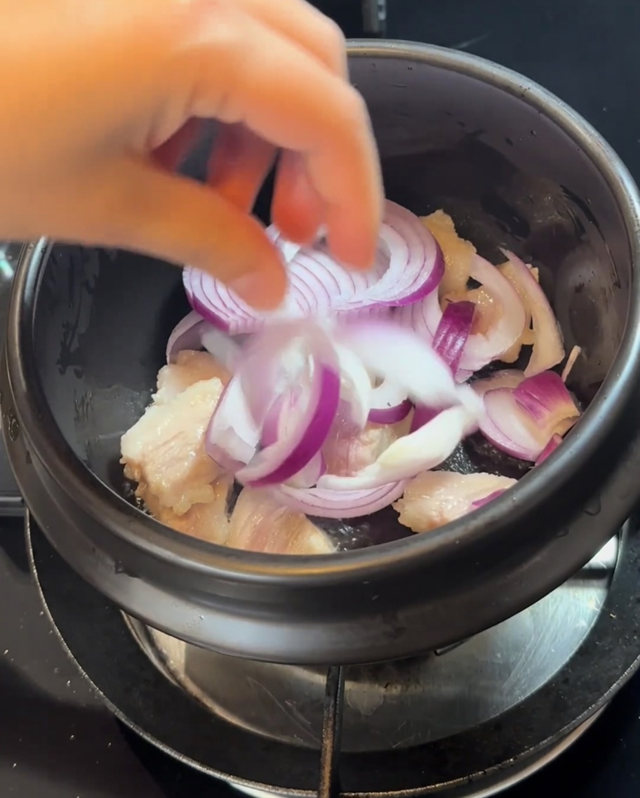 Fette di cipolla aggiunte al vaso con la carne rosolata.