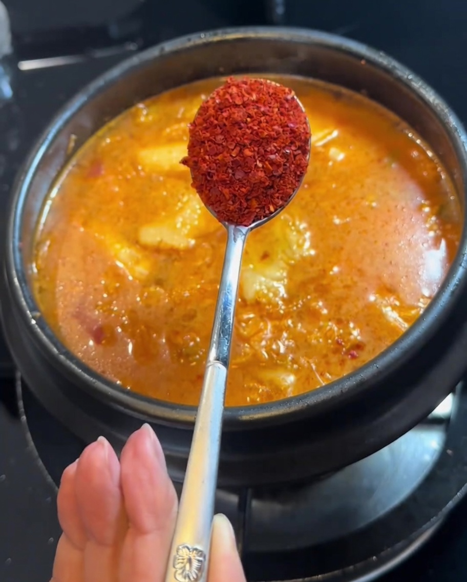 Peperoncino in polvere aggiunto allo stufato con un cucchiaio.