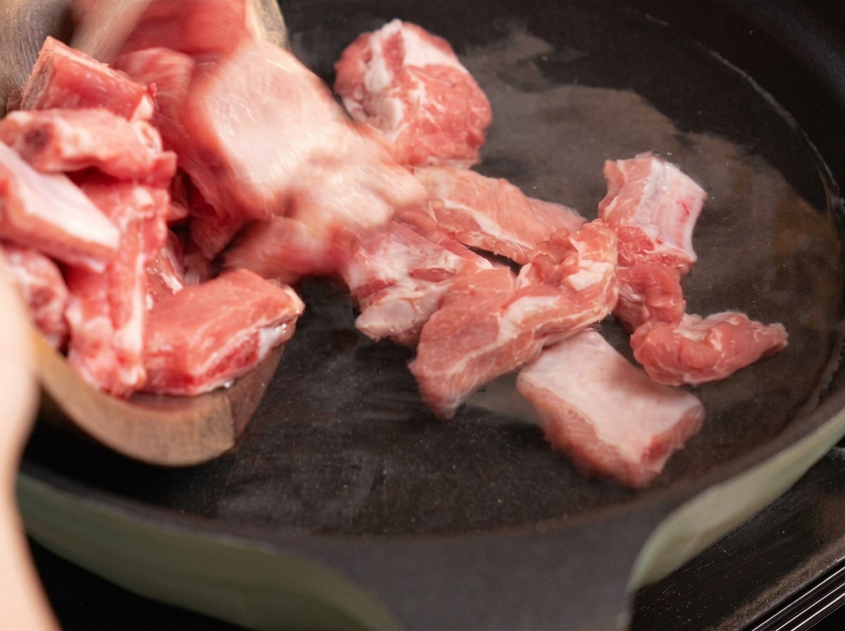 Costine di maiale che vengono sbollentate in una pentola dacqua con zenzero e cipollotti.