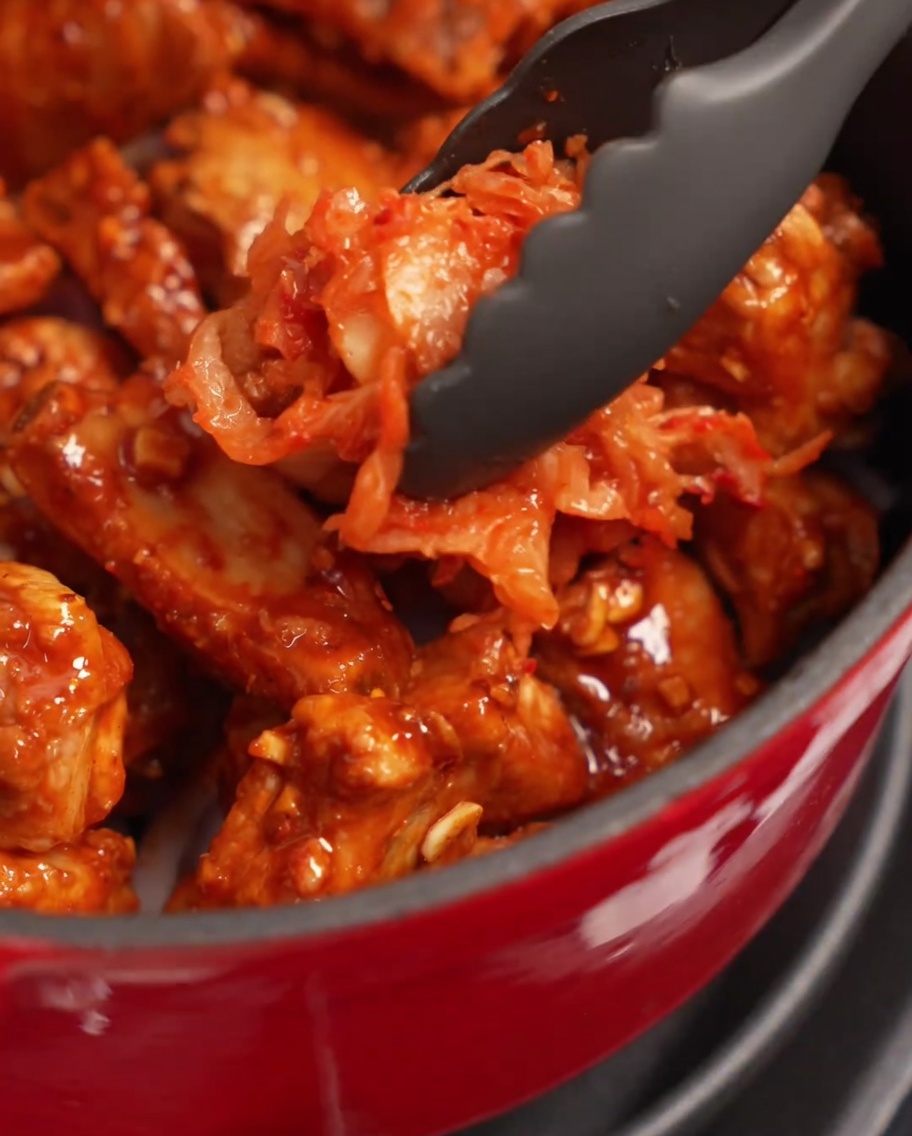 Una porzione generosa di kimchi rosso condito posizionato sopra le costine nella pentola.