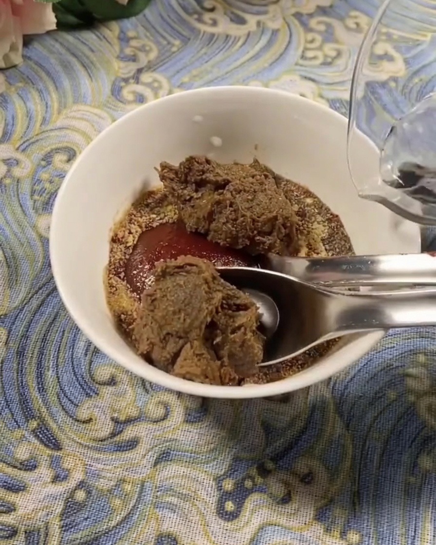 Primo piano di una ciotola bianca contenente un mix di pasta di peperoncino coreana e pasta di soia, con aggiunta di acqua fresca per diluire il condimento.