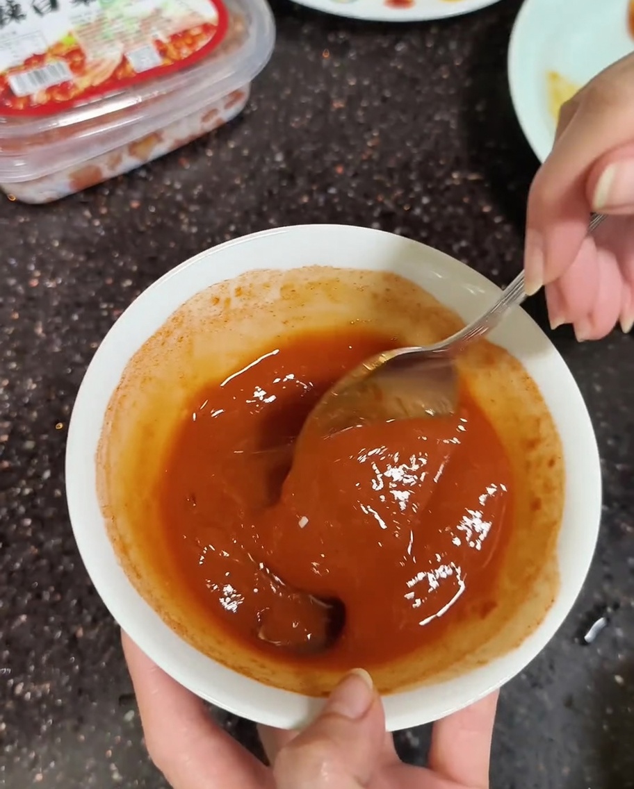 Primo piano di un cucchiaio che mescola le paste coreane con un po dacqua.