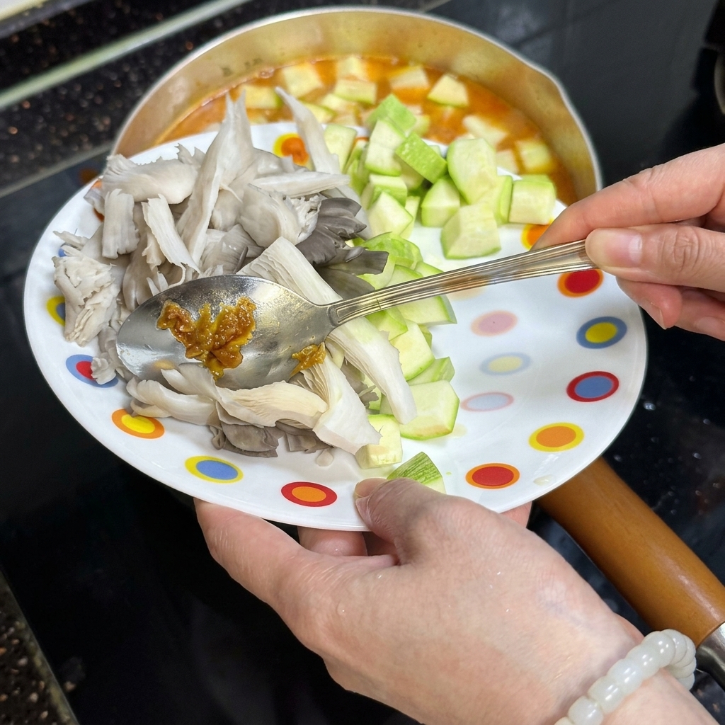 Verdure e funghi fatti scivolare da un piatto nel brodo.