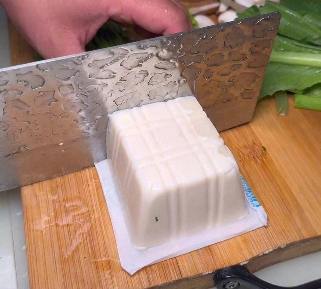 Blocchi di tofu morbido tagliati su un tagliere.