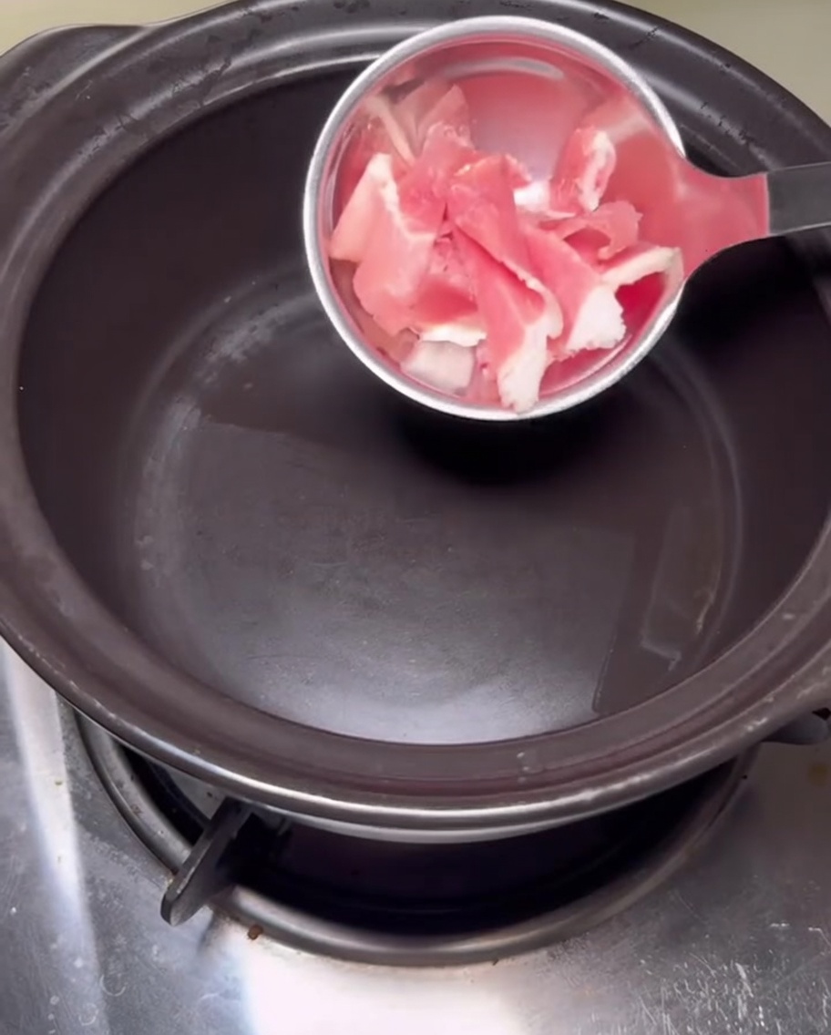 Pancetta di maiale che sfrigola nella pentola di pietra.