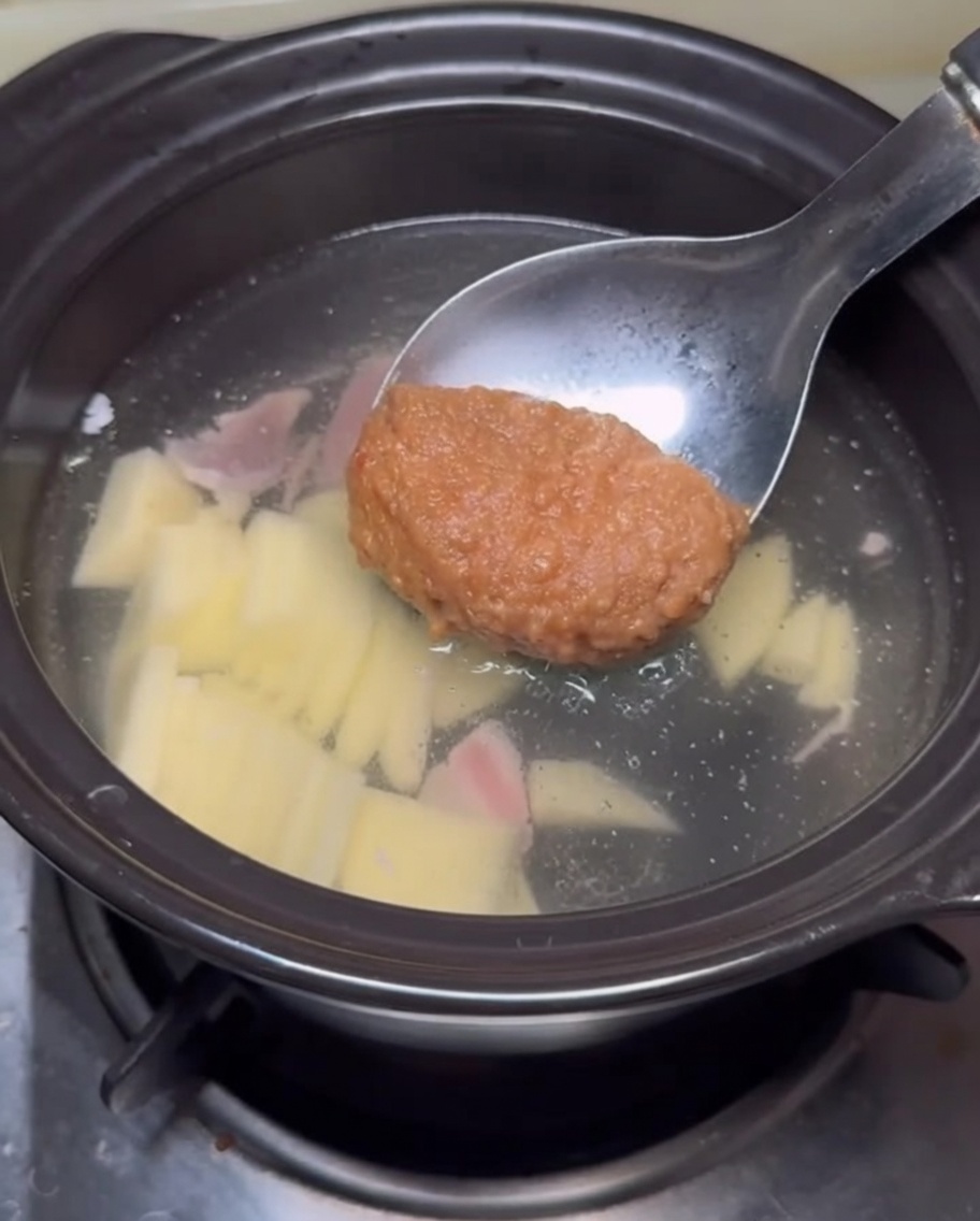 Pasta di soia aggiunta al brodo con un mestolo.