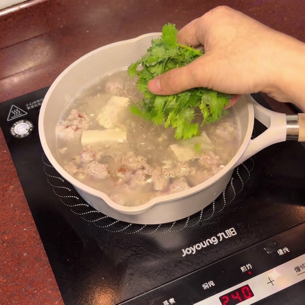 Coriandolo fresco tritato cosparso sulla pentola fumante di zuppa di tofu e prugne salate.