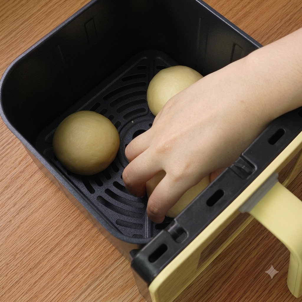 Tre palline di impasto modellate disposte ordinatamente allinterno del cestello della friggitrice ad aria.