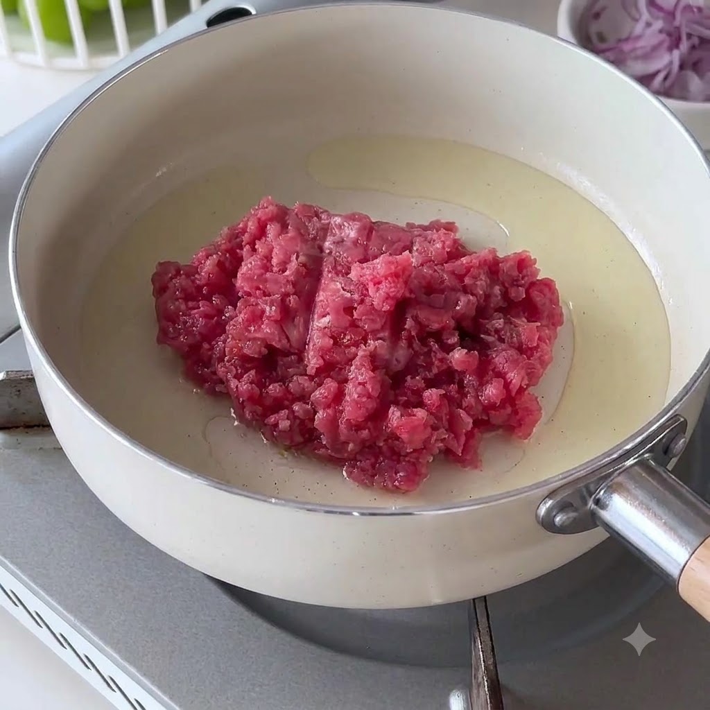 Carne macinata cruda in una padella bianca calda con olio.