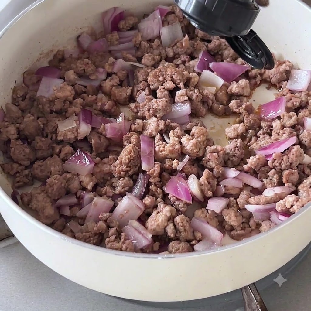 Salsa scura versata da una bottiglia sulla carne e le cipolle in padella.