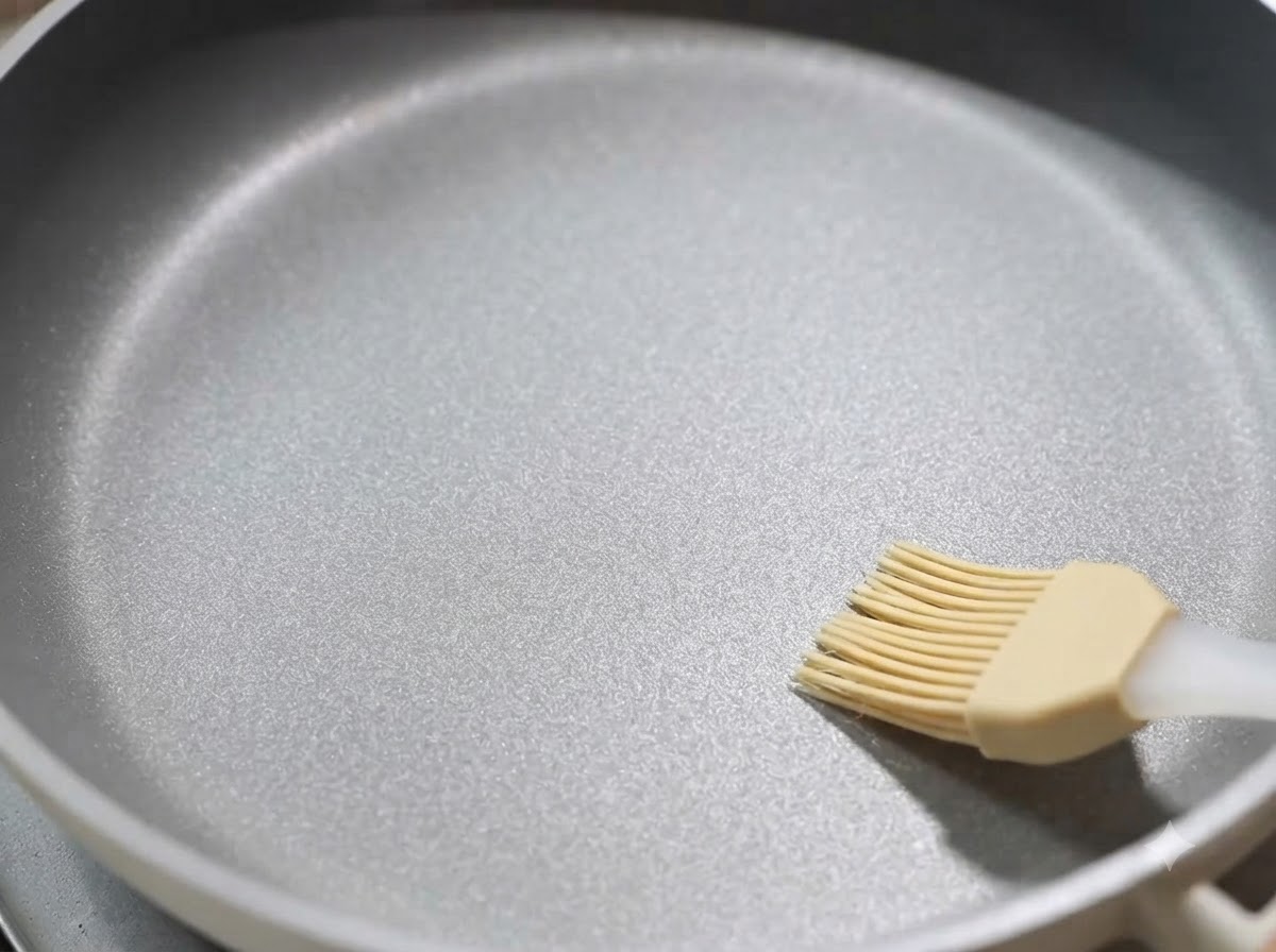Una padella antiaderente spennellata con un sottile strato di olio da cucina.