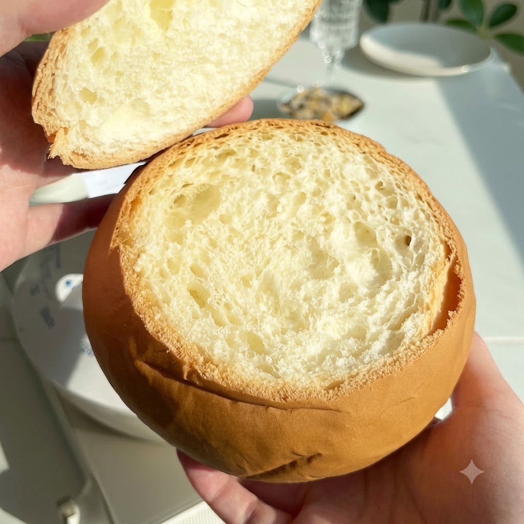Una pagnotta rotonda svuotata sollevata con il coperchio rimosso accanto.