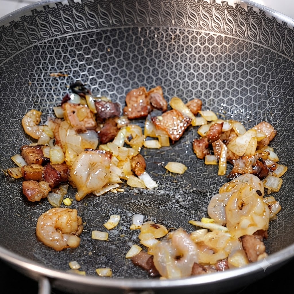 Gamberi, pezzi di pancetta e cipolle tritate saltati insieme in un wok.