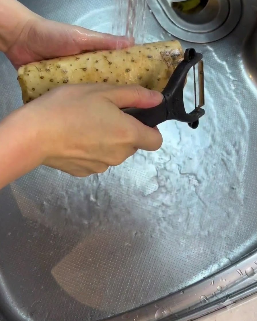 Uno yam sbucciato risciacquato e pulito sotto lacqua corrente in un lavandino.