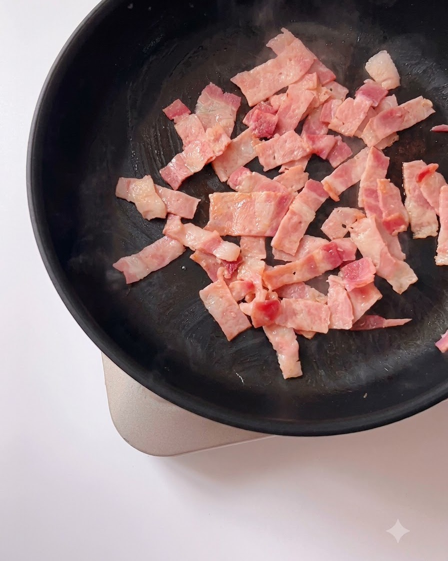 Tuorli duovo salato schiacciati mescolati con pezzi di pancetta rosolata che sfrigolano in una padella.