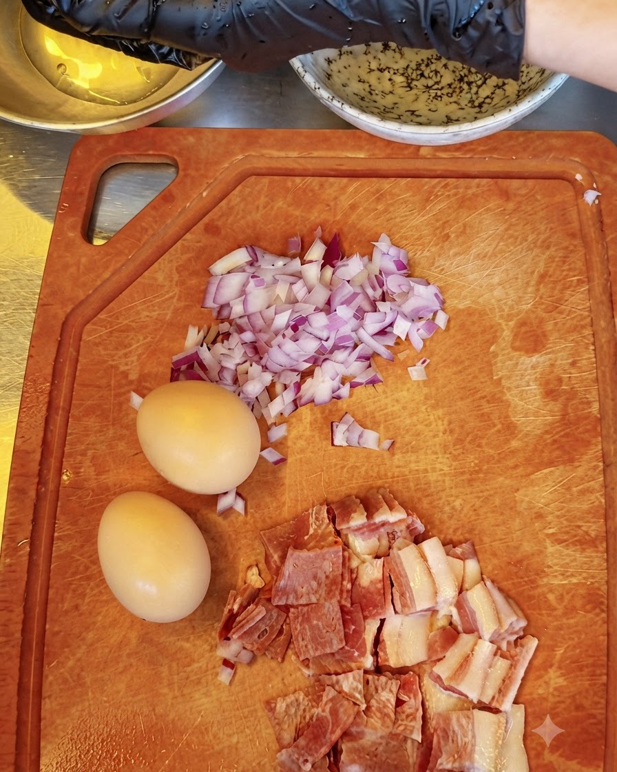 Una persona che separa i tuorli duovo crudi con le mani guantate, tenendoli sopra una ciotola mentre altri ingredienti si trovano su un tagliere.