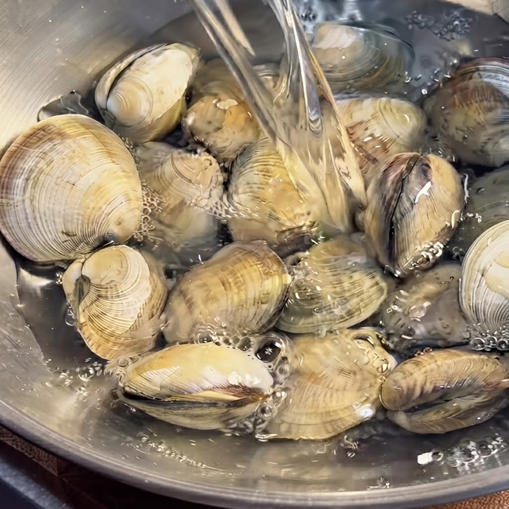 Vongole immerse in una ciotola dacqua e pulite accuratamente a mano.