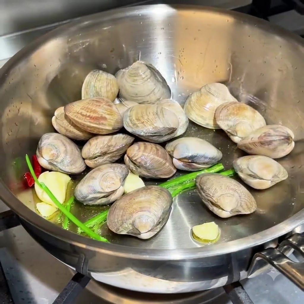 Vongole sparse nella padella insieme allaglio e alle radici di erba cipollina.