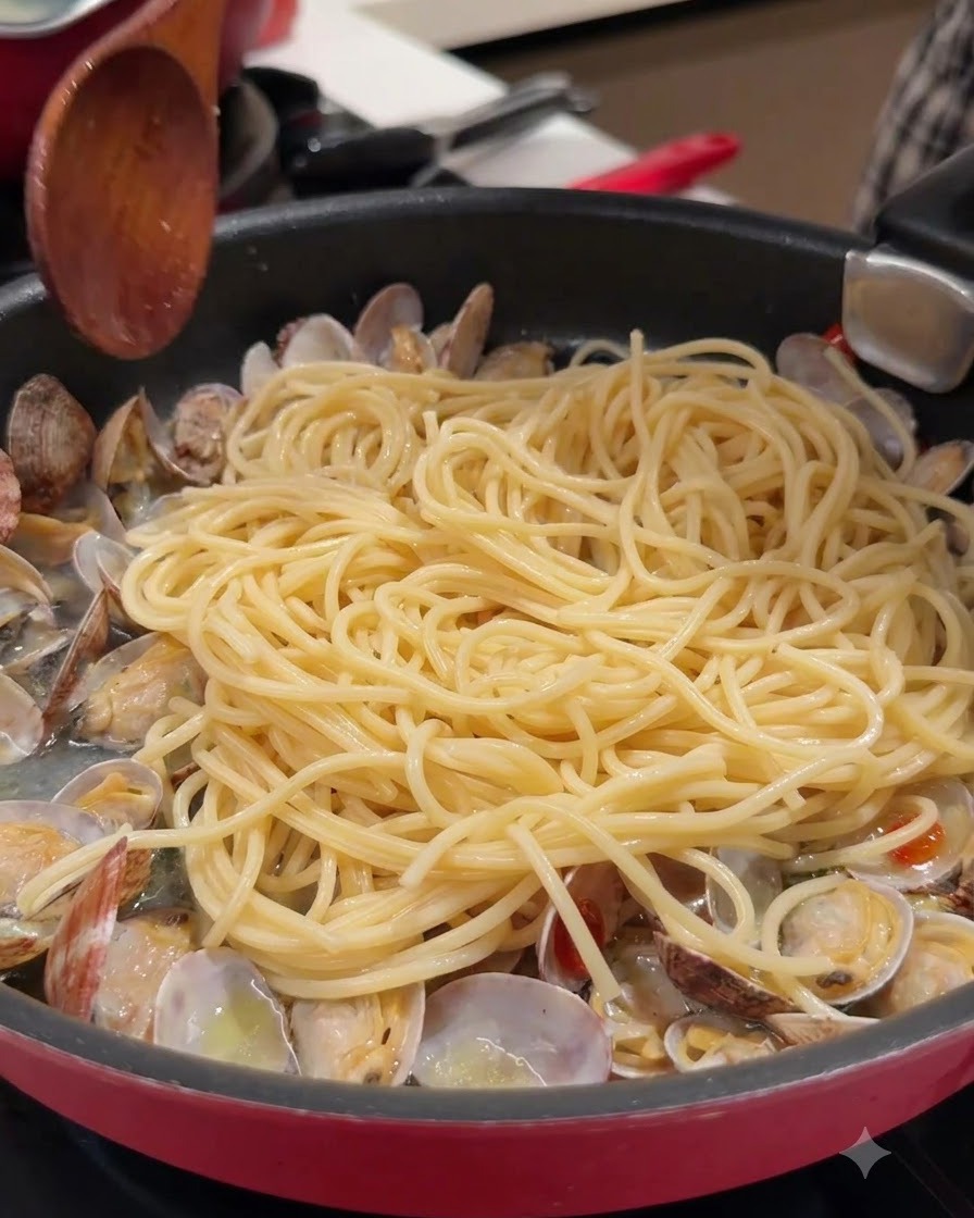 Un cucchiaio di legno e spaghetti in una padella con vongole aperte e brodo.