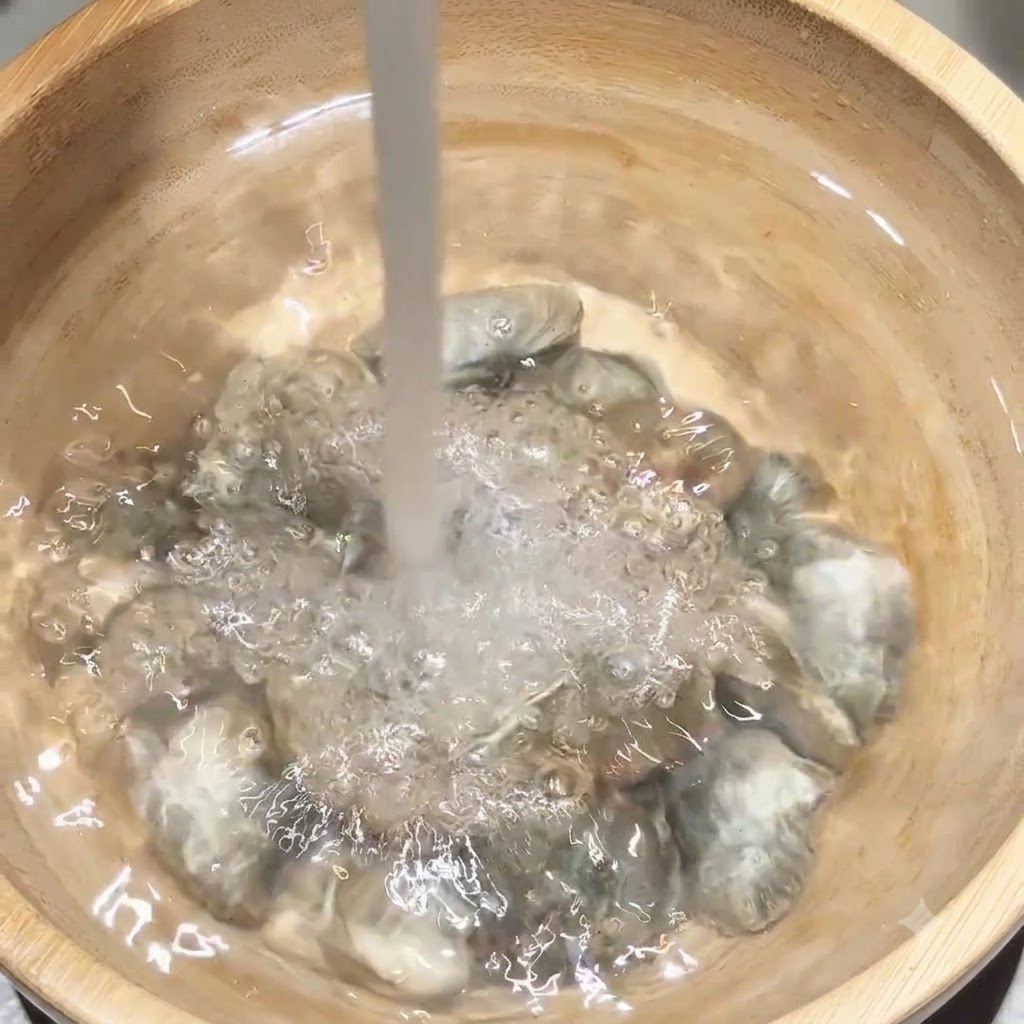 Acqua fresca che scorre direttamente su un gruppo di vongole allinterno di una ciotola di legno.
