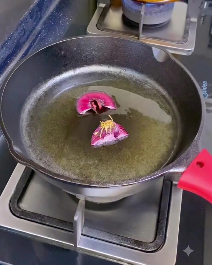 Una padella in ghisa su un fornello contenente olio doliva e due pezzi tagliati di radici di scalogno.