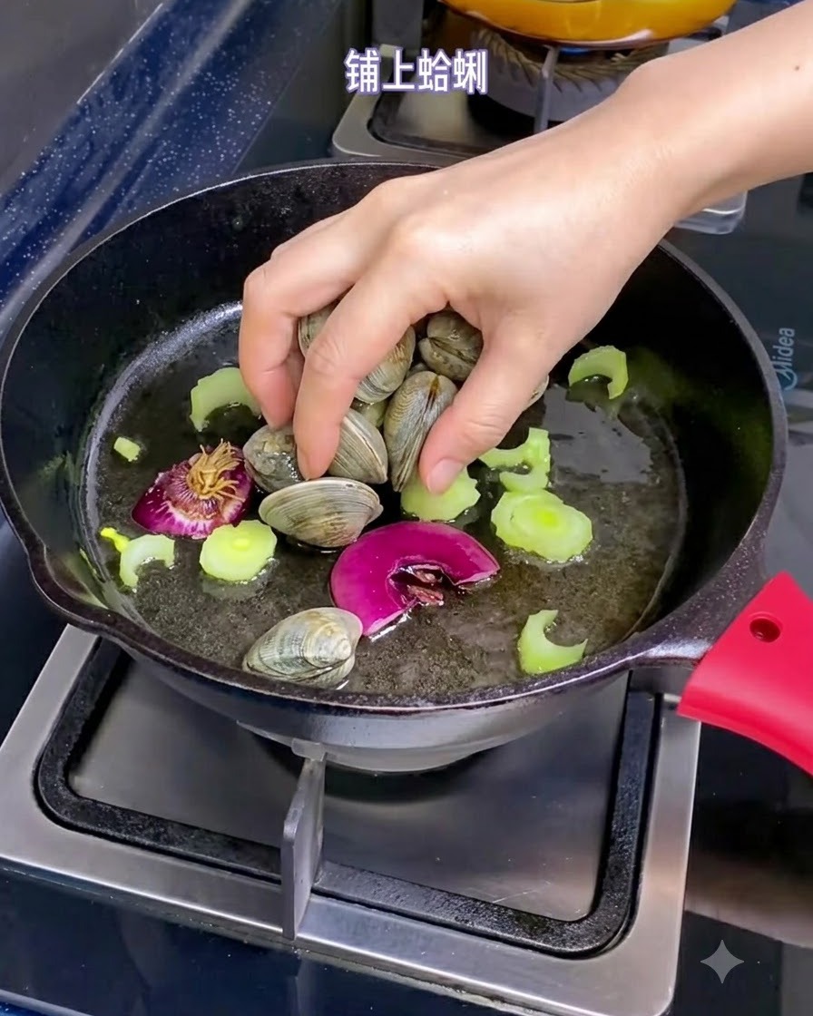 Una mano che posiziona vongole fresche in una padella riempita con olio doliva, pezzi di scalogno e sedano affettato.