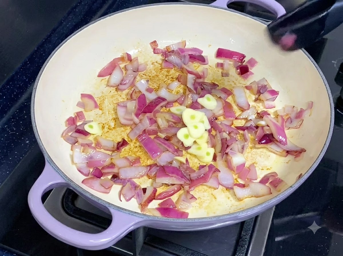 Fette di aglio fresco appena tagliate aggiunte a una padella di cipolle rosse saltate.
