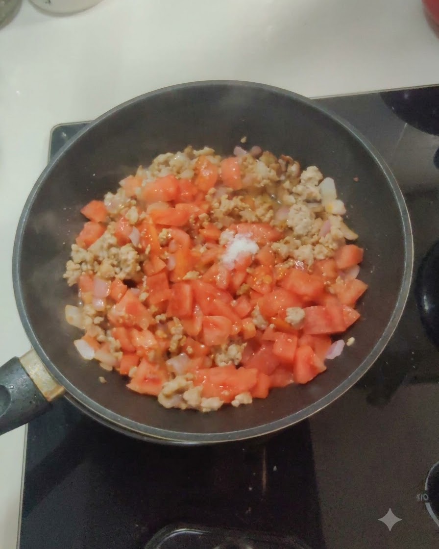 Sale bianco e zucchero cosparsi sopra il composto di pomodoro, cipolla e carne in padella.