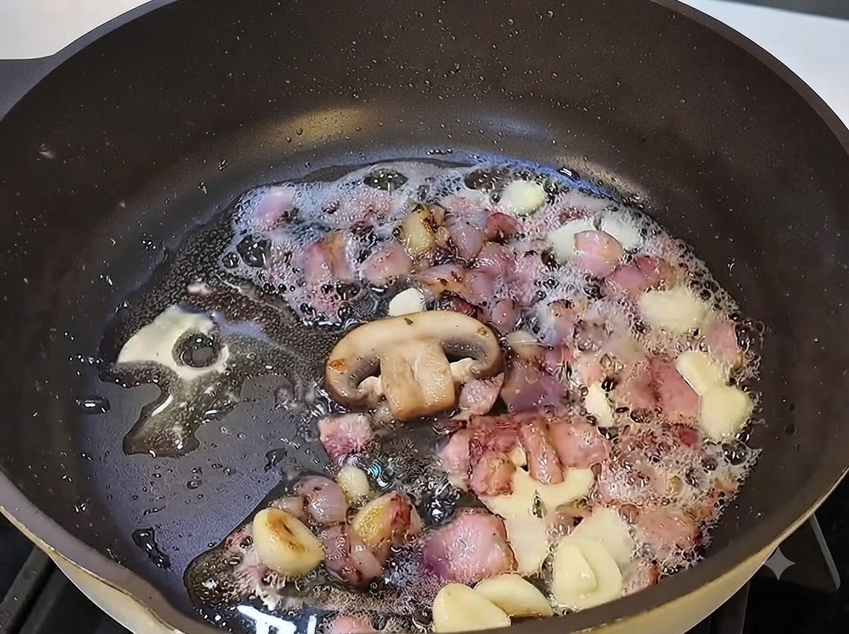 Funghi affettati che cuociono nella padella con pancetta e aglio.